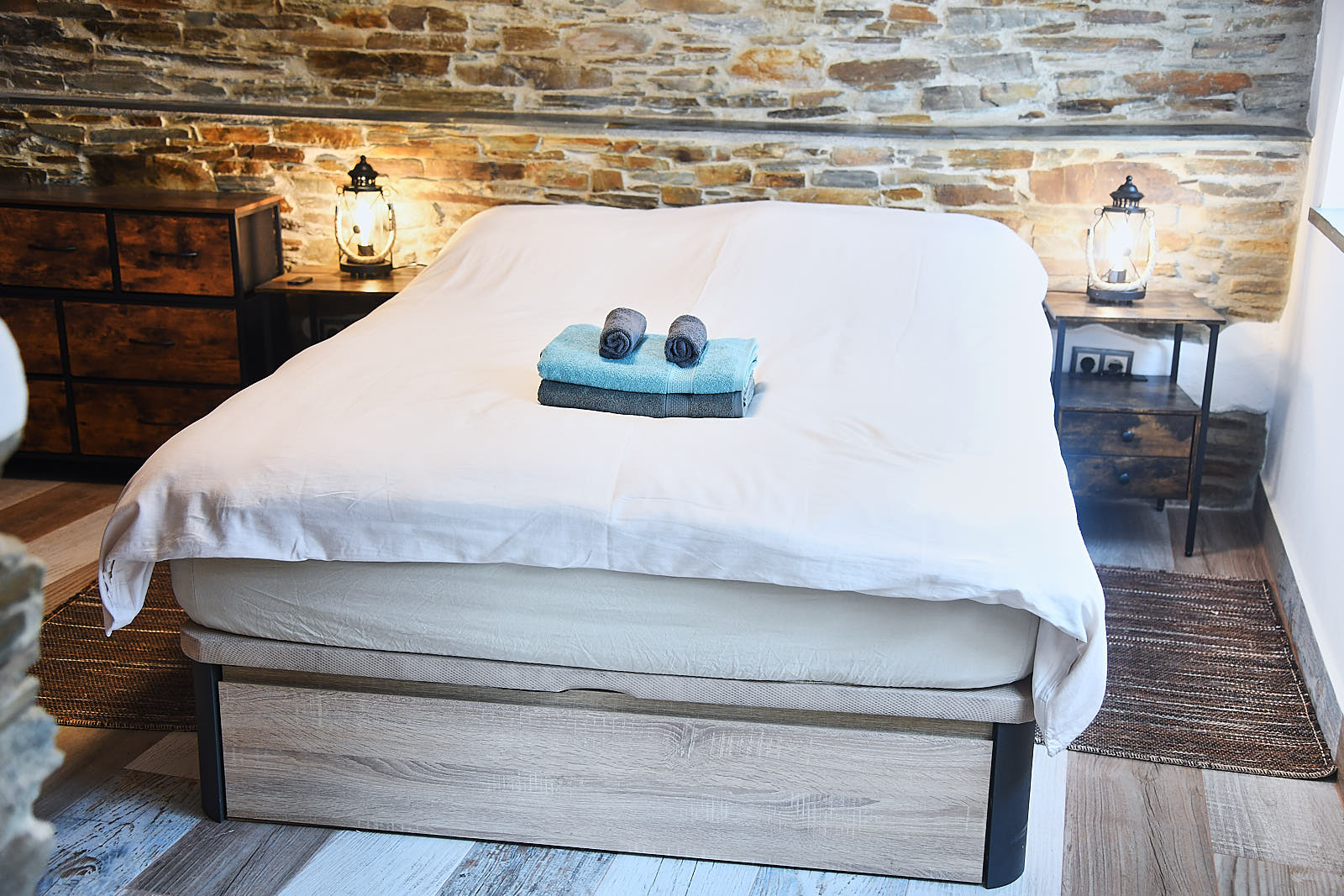 Casa da Égua bedroom with white bedding, blue-framed windows and exposed stone wall