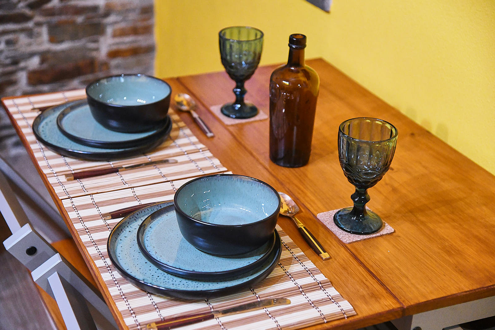 Blue ceramic table setting with dark goblets on the wooden dining table
