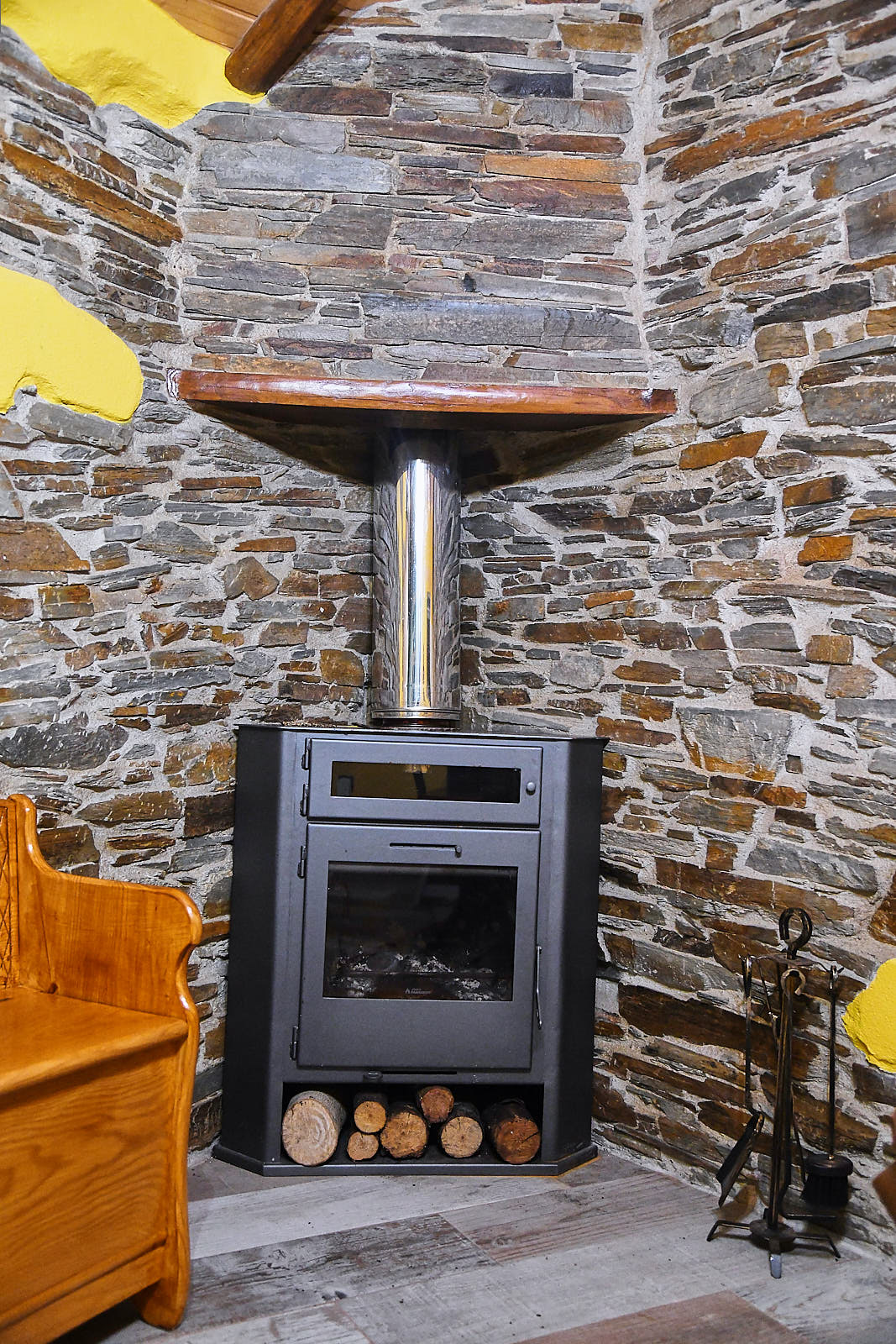 Wood-burning stove and chimney against the exposed schist wall
