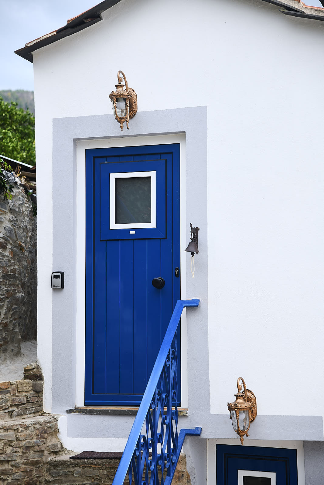 Casa da Égua blue entrance door framed by blue railings and bronze lanterns