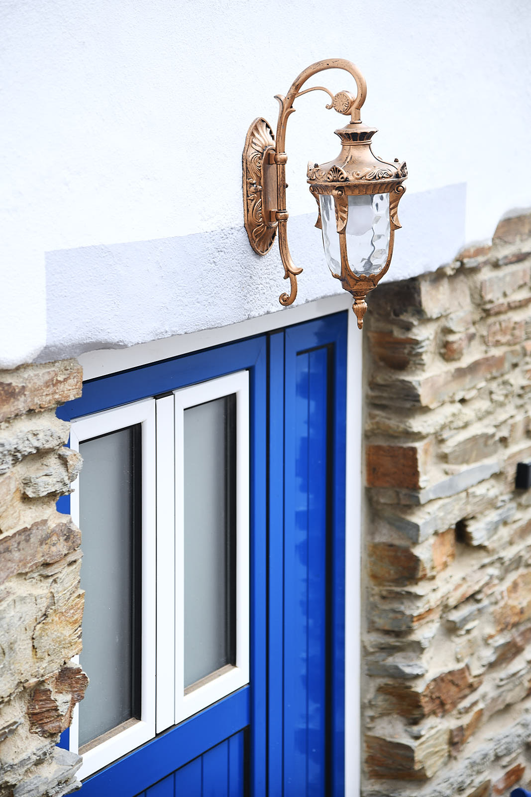 Blue window with a terracotta pot of lavender and a traditional wall lantern