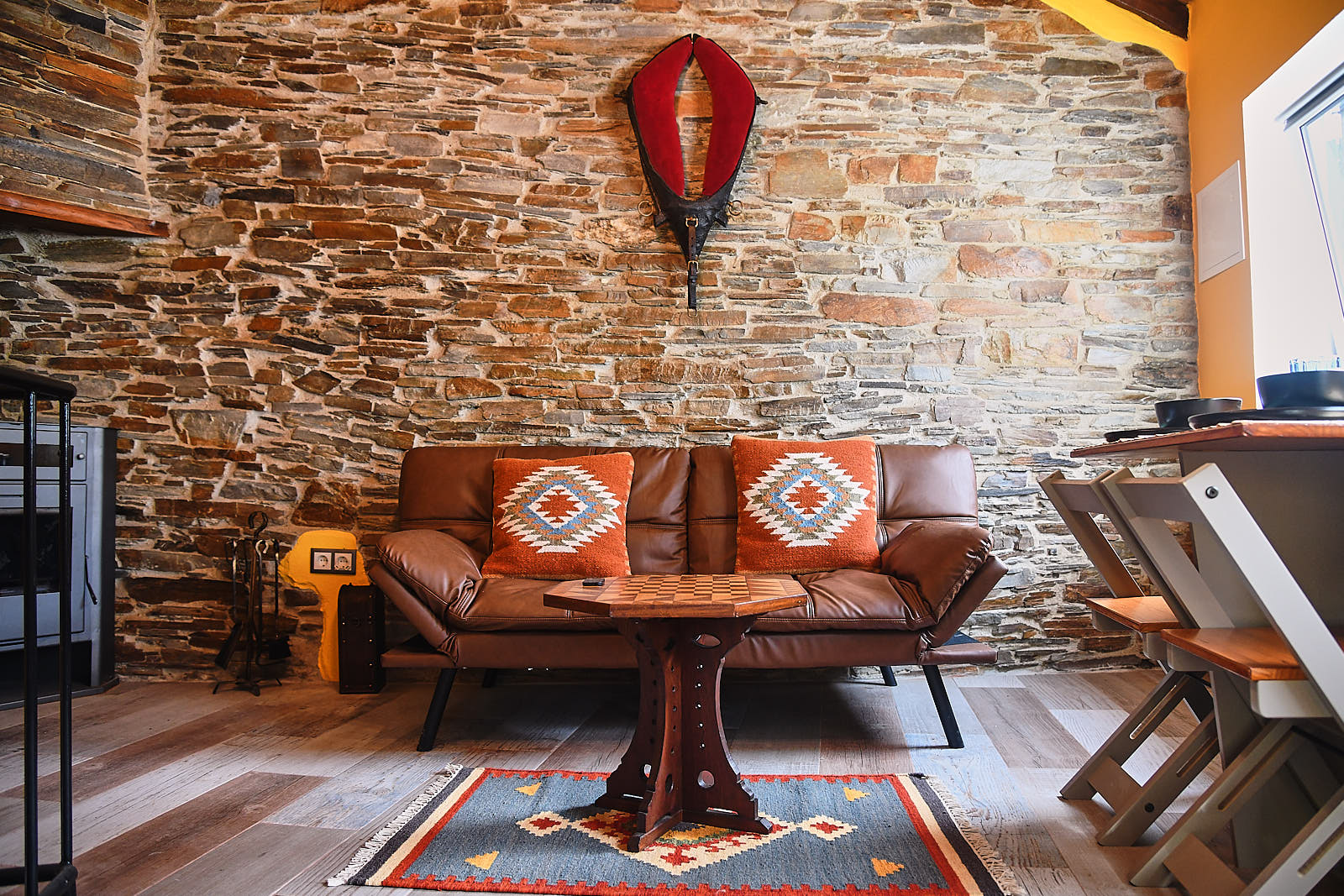 Casa da Égua living room with a leather sofa, patterned cushions and exposed schist wall
